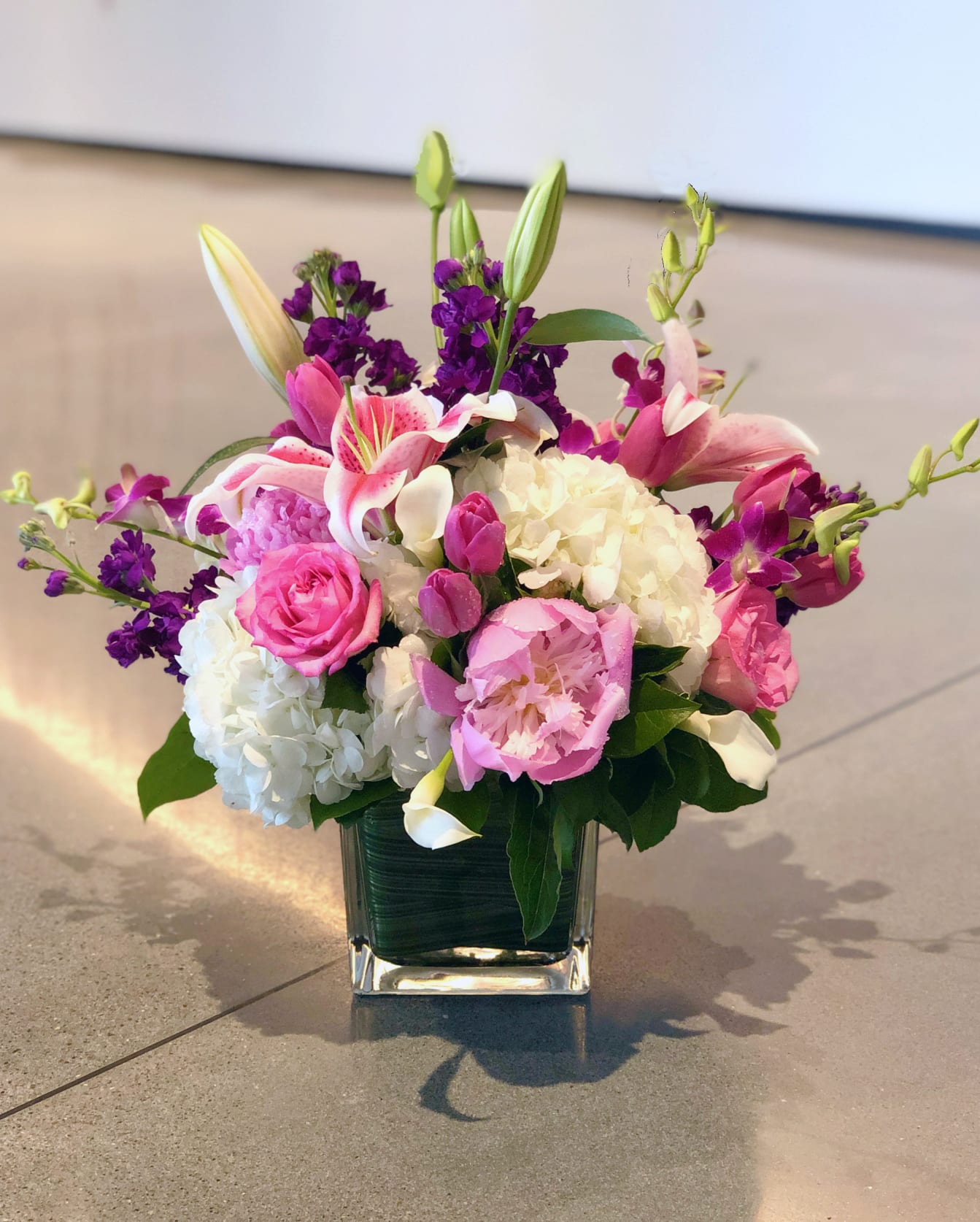Pink and white floral arrangement in a square glass vase