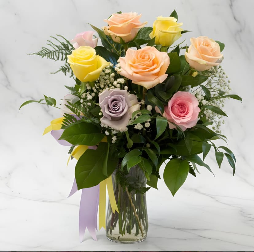 Springtime Dozen Roses - A fresh, seasonal twist on the classic dozen roses. This arrangement features a beautiful mix of pastel roses in shades of peach, yellow, blush, and lavender, accented with delicate baby’s breath and lush greenery. Designed in a clear glass vase and finished with soft spring ribbon, it’s bright, airy, and perfect for celebrating the season, birthdays, or sending a cheerful surprise.