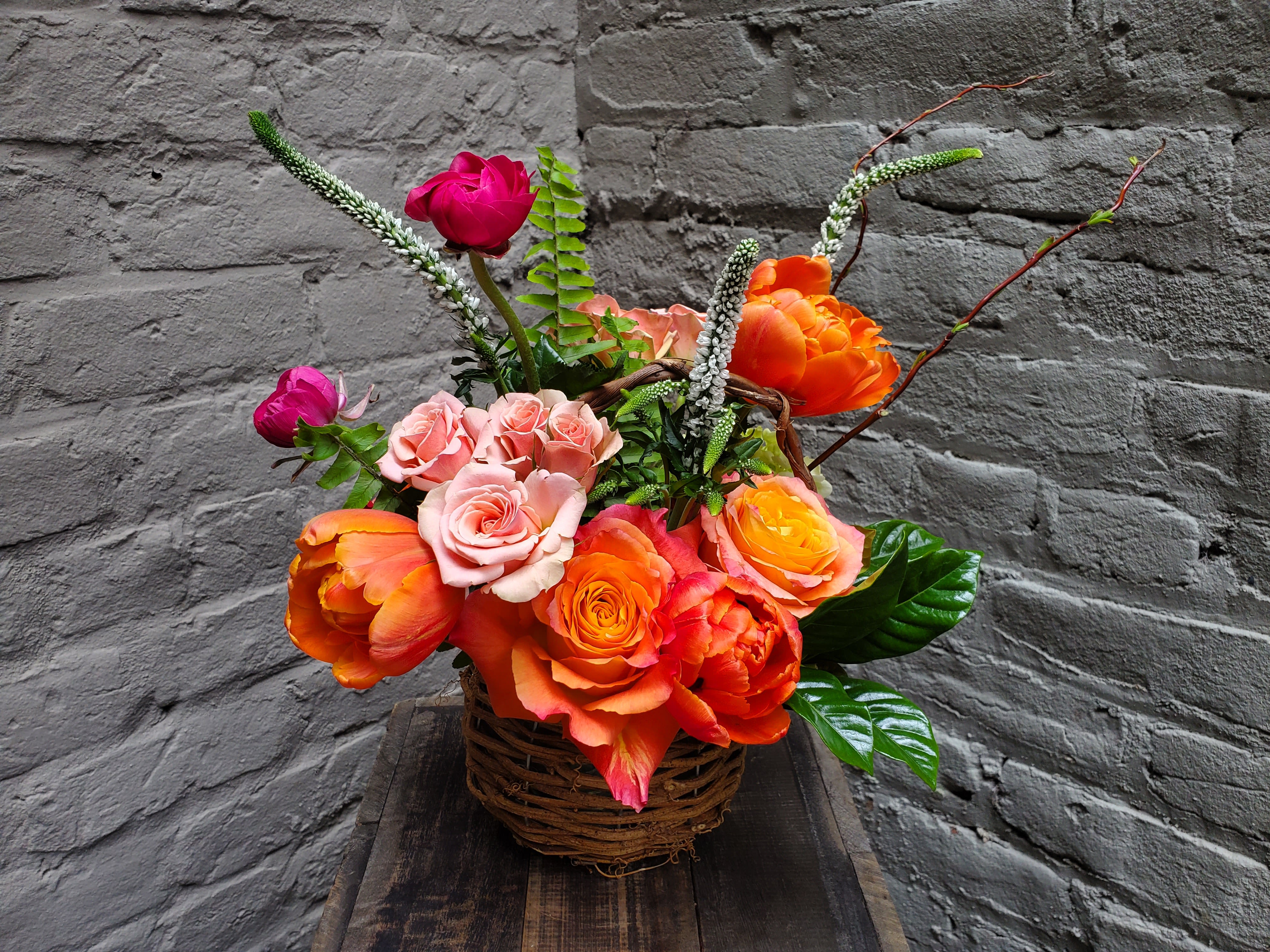 Li'l Easter Basket - Easter's on its way with this sweet, sunshiney basket arrangement of colorful delights!  Includes orange and peach roses accented by locally grown tulips and willow branching.  The standard arrangement measures approximately 14" tall x 12" wide.