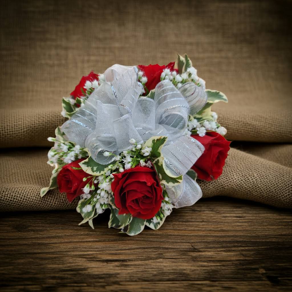 Small bouquet of red roses with white ribbon and variegated greenery