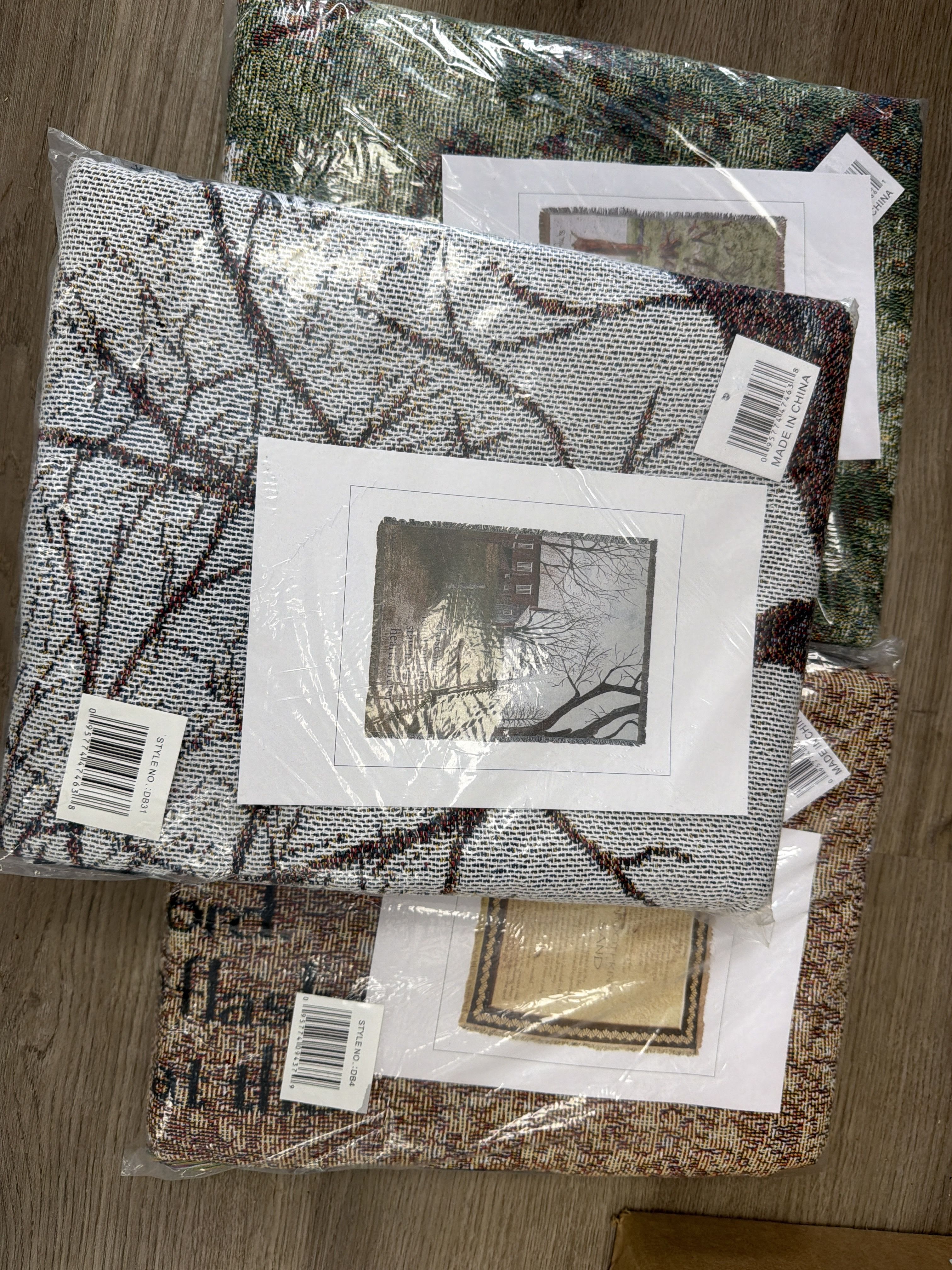 Stack of packaged woven decorative textiles with printed scene inserts