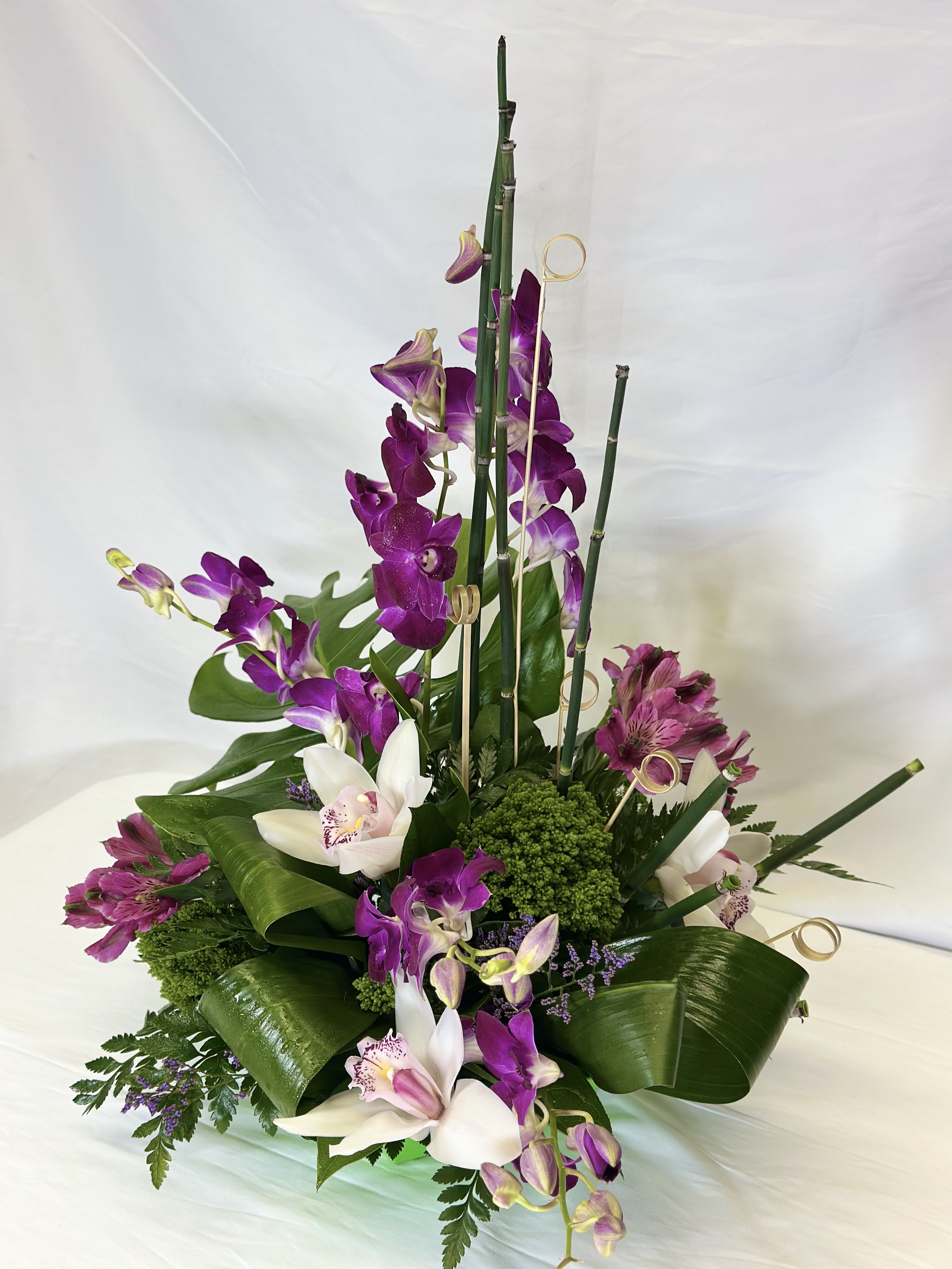 Namaste Flowering Orchids - This is an absolutely stunning design featuring dendrobium and cymbidium orchids. The gentle floral lines, contrasting with the sleek vertical elements,  and intense greenery, bring a sense of Zen to this Leary's Flowers exclusive arrangement. This will be the perfect gift for any orchid lover, or for someone who truly appreciates flower artistry.   In order to ensure the freshest possible flowers, we may design your arrangement using colors other than the ones featured here.