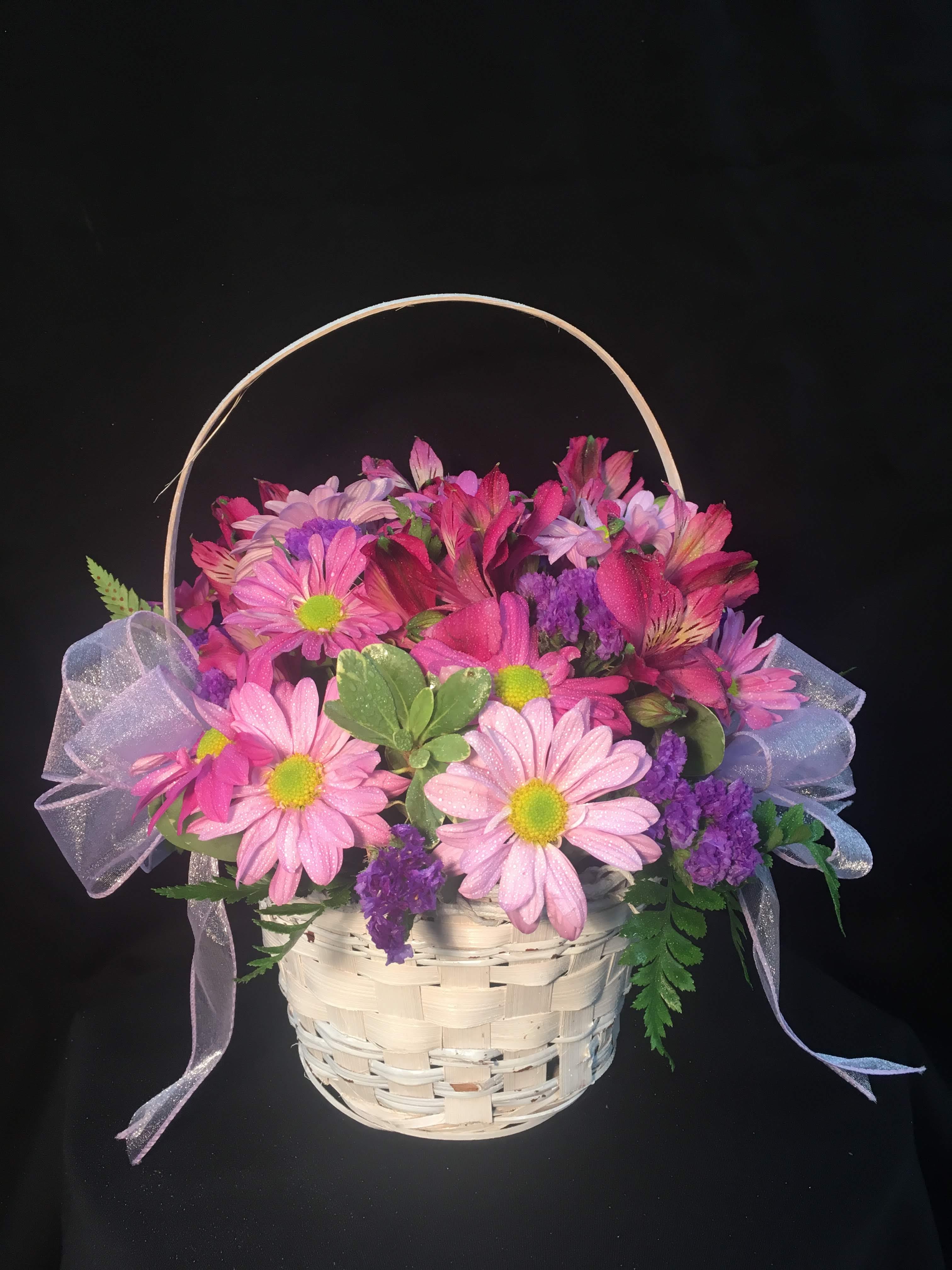 Pink and purple daisy basket arrangement with sheer ribbon bows in a white woven basket