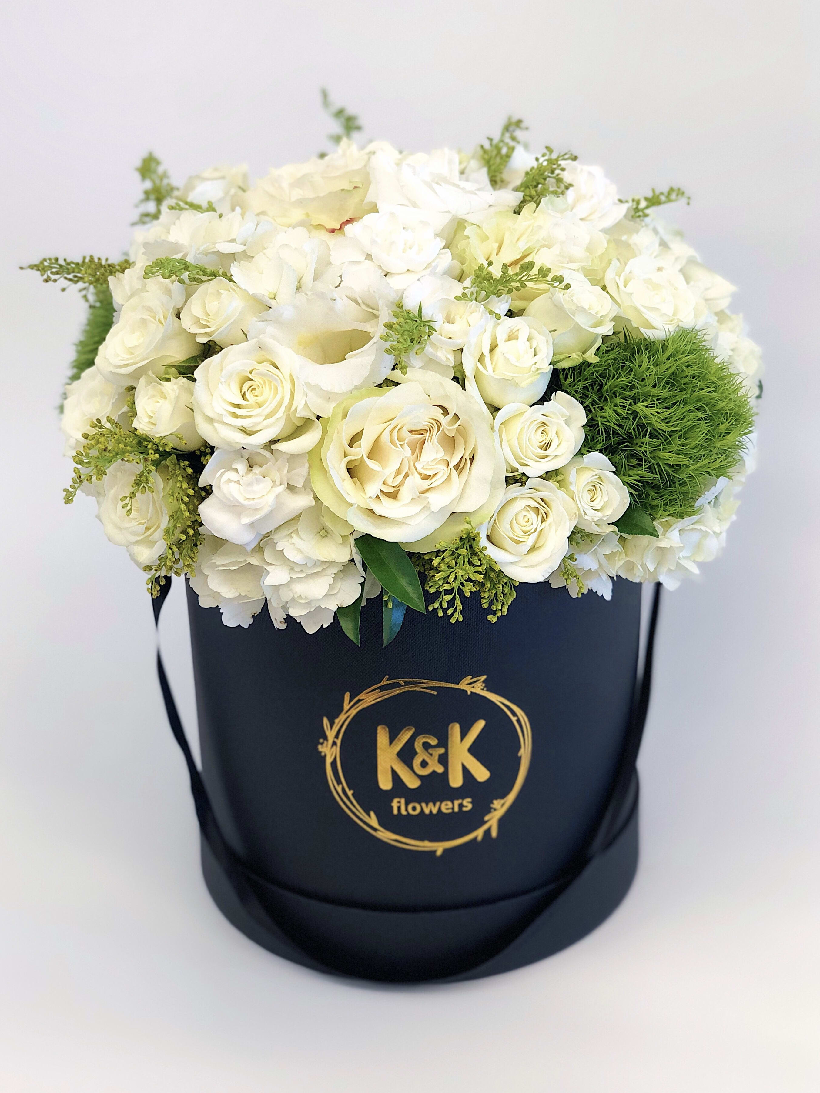 White rose arrangement in a black hatbox with gold logo