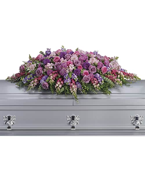 Lavender Tribute Casket Spray - Honor her femininity and generous spirit with a blanket of sweetly scented lavender, pink and purple flowers that create a magnificent final tribute, sincerely expressing devotion and love. Gorgeous flowers such as lavender and pink roses, pink snapdragons and alstroemeria, purple and lavender chrysanthemums. All are entwined with eucalyptus, huckleberry and ming fern.