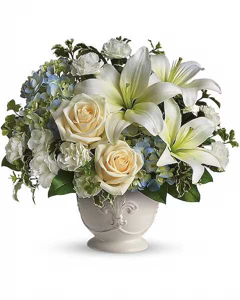 Beautiful Dreams by Teleflora - Soothing and respectful. Calm and compassionate. This beautiful collection of white and light colored blossoms will deliver your loving thoughts perfectly. Tasteful flowers such as light blue hydrangea, crÃ¨me roses, white asiatic lilies, miniature carnations and more are delivered in a lovely white French Country Pot.