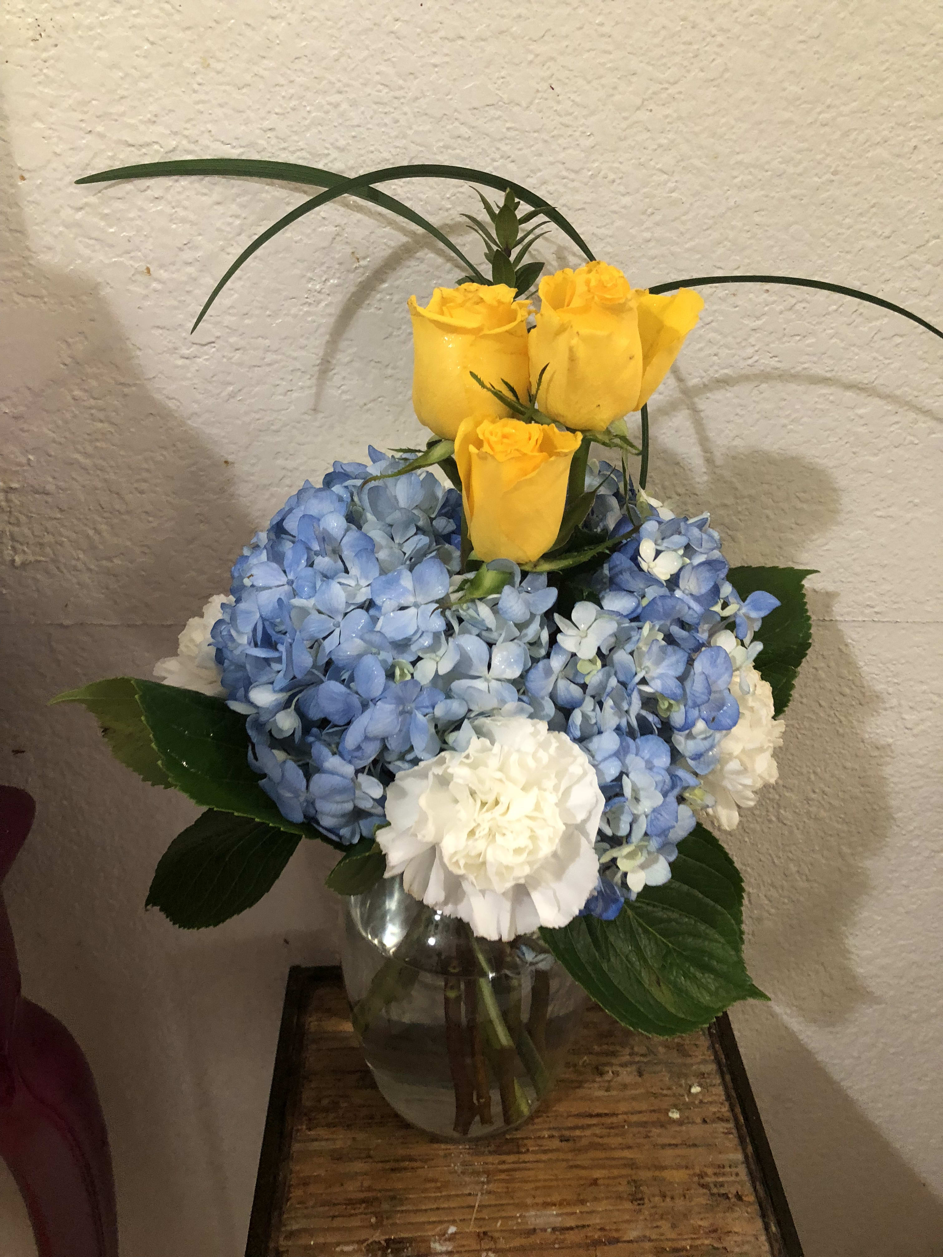 The Yellow Rose of Texas - A custom design by Wonderland Flowers - Just like the song, but we've added some blue hydrangea circled around our beautiful yellow roses, with some white carnations as well. 