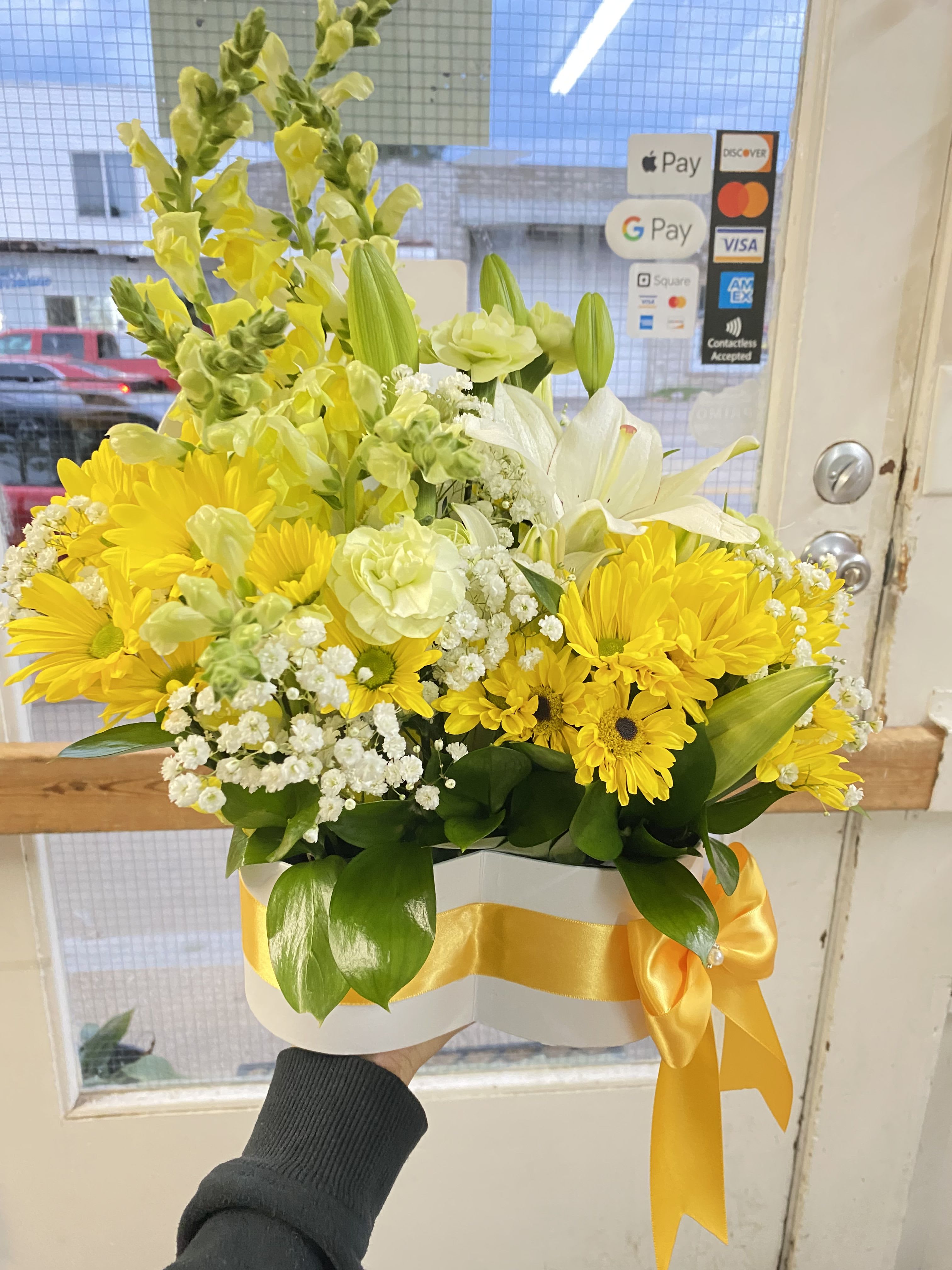Yellow and white mixed flower arrangement in a white hatbox with a yellow ribbon bow