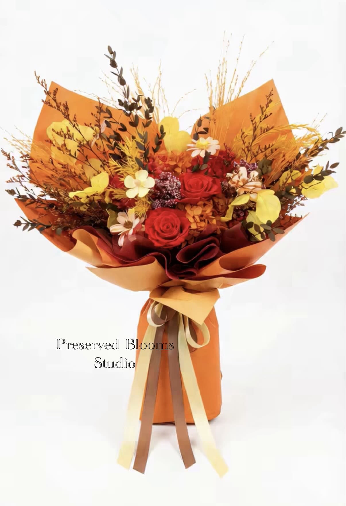 Tall bouquet of red and yellow flowers with dried accents wrapped in bright orange paper with ribbons