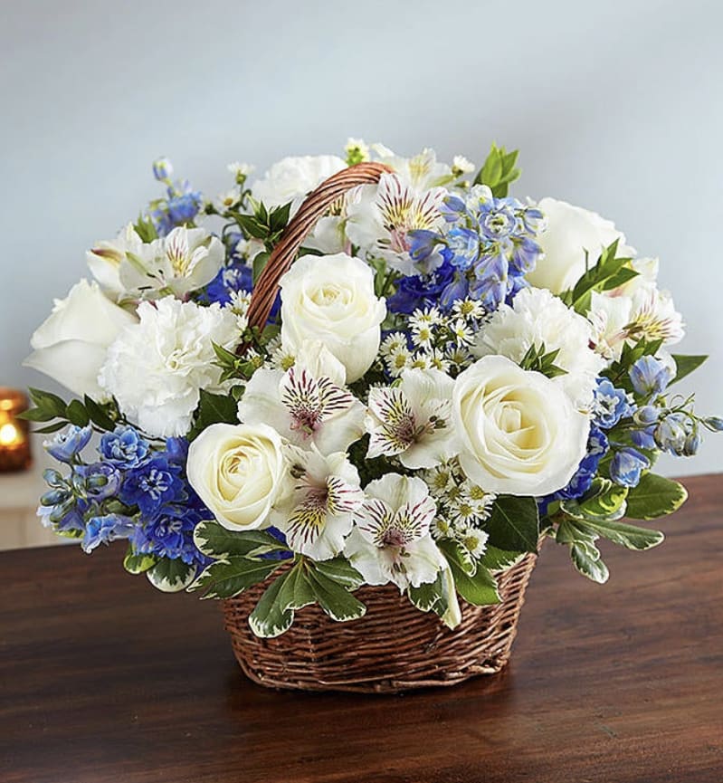 White and blue mixed flower basket arrangement on a wooden table