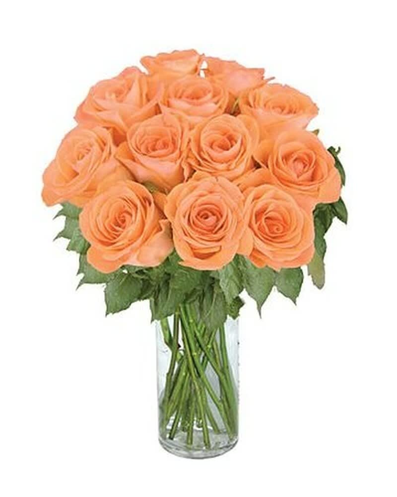 Peach rose bouquet arranged in a clear glass cylinder vase
