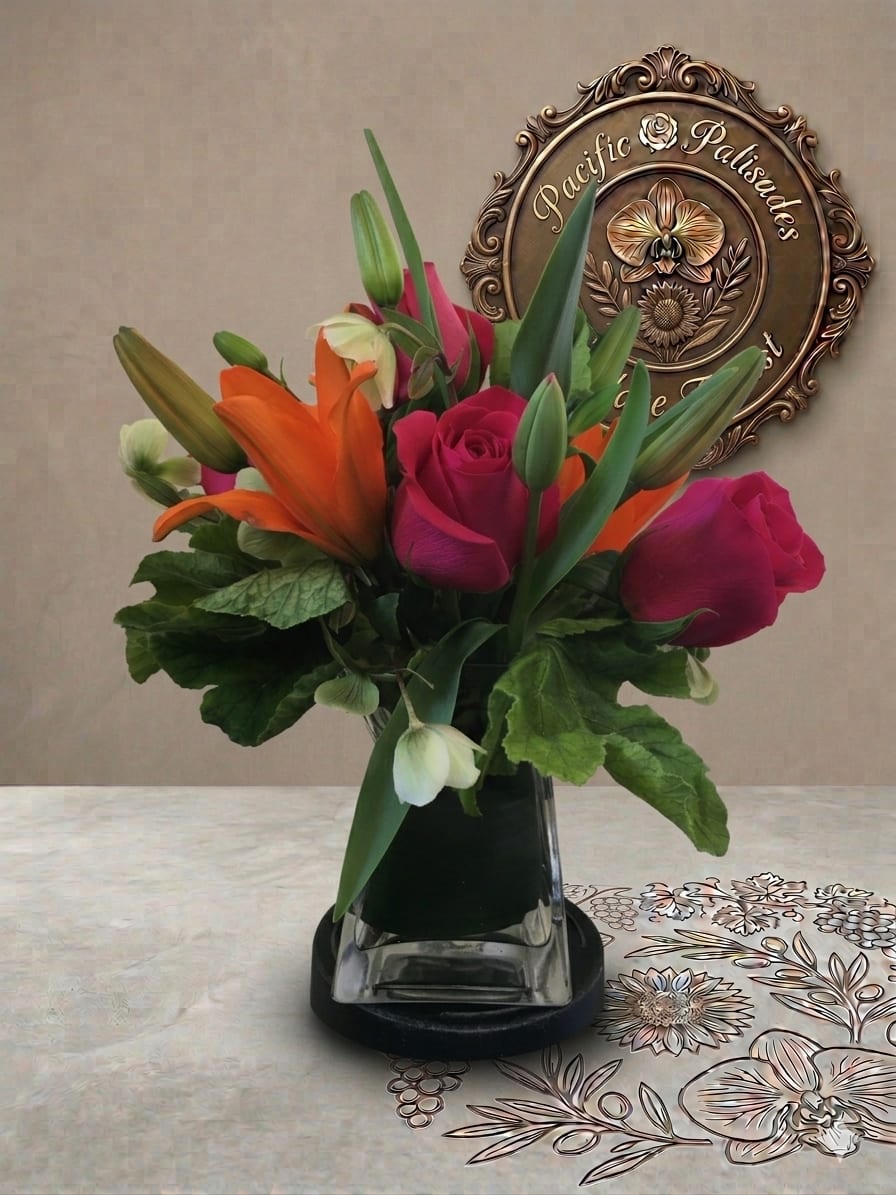 The Other Woman - A bold, modern arrangement featuring vibrant orange lilies and deep pink roses, accented with sleek greenery and soft white hellebore blooms. The design feels striking and contemporary, with clean lines and rich color contrast that create a confident, sophisticated look.