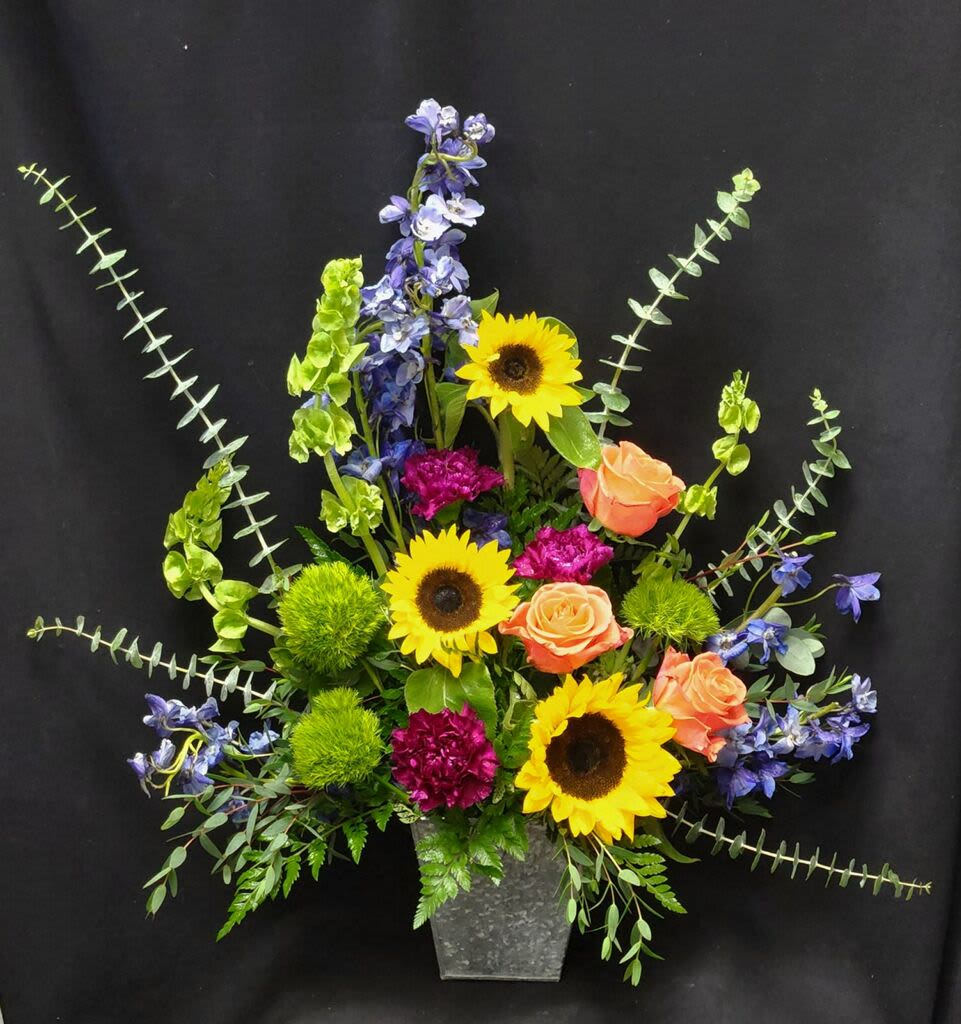 My Sunshine - One sided bright arrangement including, sunflowers, roses, bells of irleand, delphinium, mixed greens including spiral eucaliptus and more