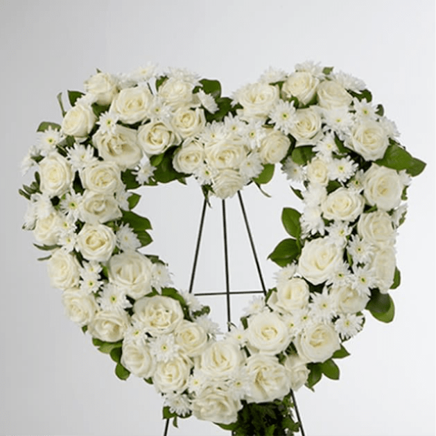 Heart-shaped standing wreath of white roses and daisies on a metal easel.