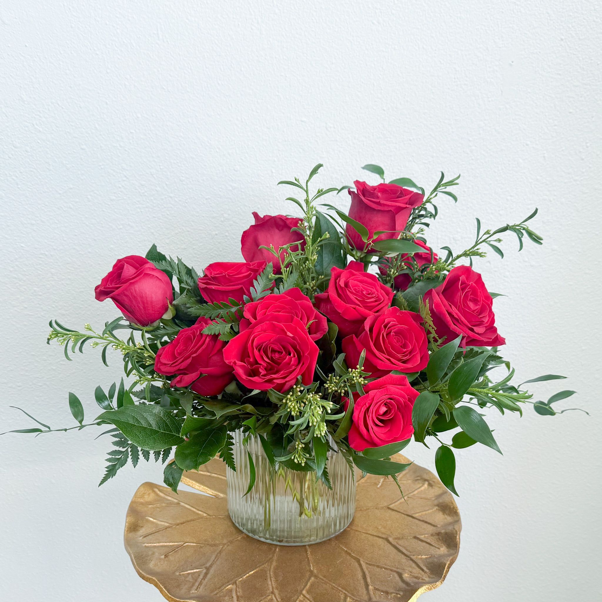 The Lush Dozen  - The Lush Dozen is for the person who is loves a classic but with a stylish update. Roses are densely arranged in a ribbed cylinder with deep mixed greenery.  Upgrade to Deluxe for 18 roses; Premium for 24 roses in a larger ribbed vase.