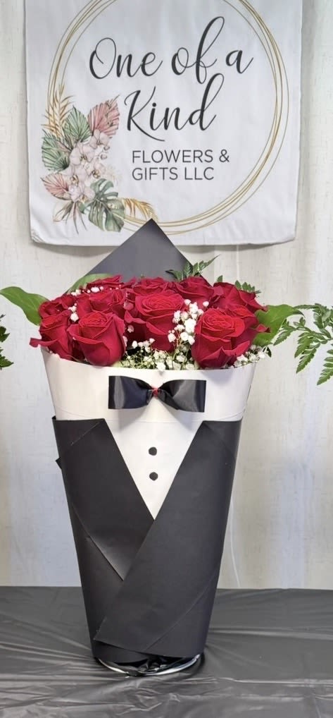 Gentleman Elegance -  A sophisticated and modern arrangement designed in the shape of a classic tuxedo, perfect for making a lasting impression on special occasions. It features a dozen fresh red roses, delicate white accent flowers, and lush greenery, all beautifully wrapped in premium tuxedo-style paper with a bow tie detail. Ideal for graduations, birthdays, anniversaries, or any elegant celebration.