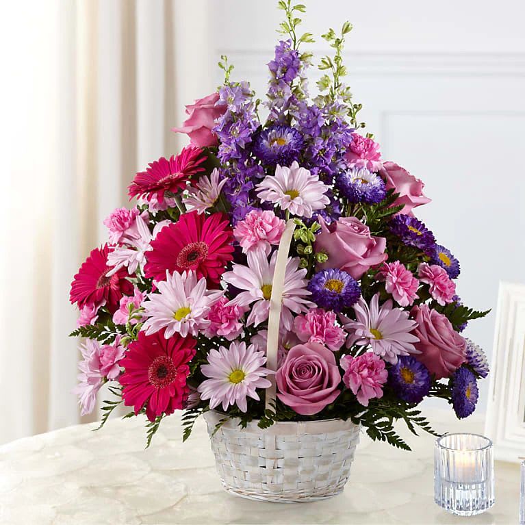 Pastel Flowers Basket - Lavender roses, fuchsia gerbera daisies, lavender daisies, purple larkspur, purple matsumoto asters, pink mini carnations and lush greens are arranged to perfection in a round whitewash handled basket.