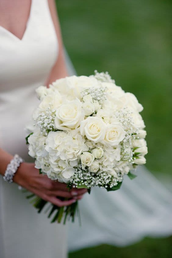 Bridal Bouquet- "Fantasy" - A petite yet impactful arrangement of hydrangea, ivory roses, and spray roses accented with soft greenery. Designed with open stems and finished with an ivory satin ribbon wrap, offering a lush, romantic look with graceful, compact elegance.