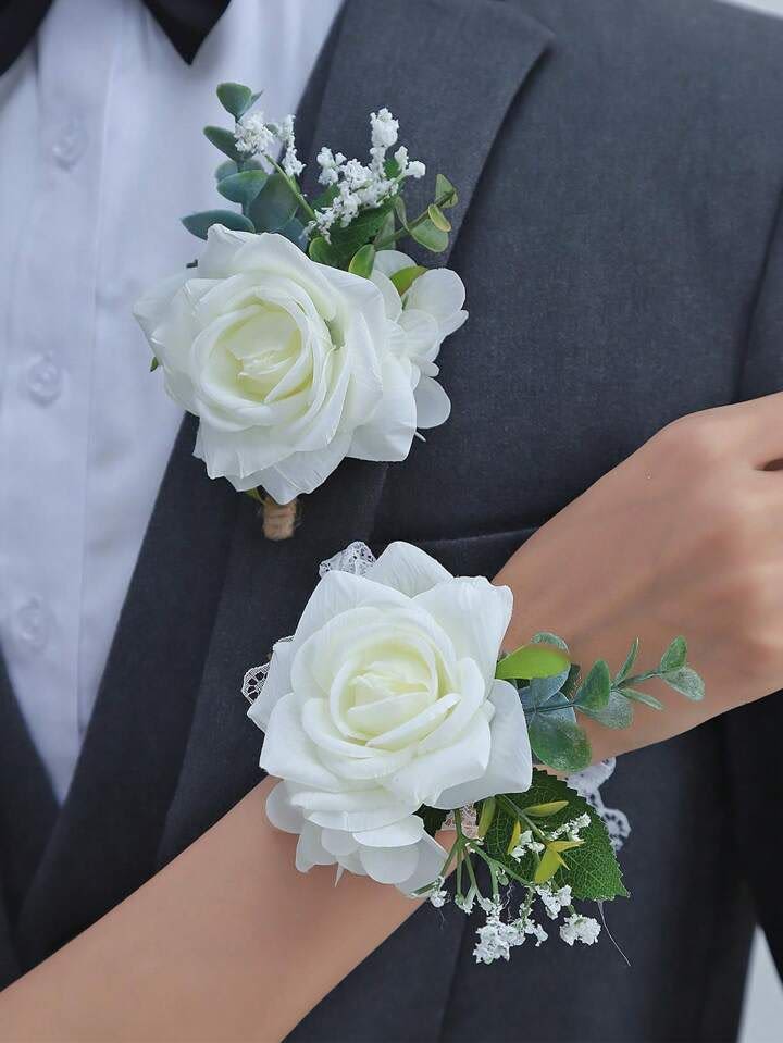 Matching white rose boutonniere and wrist corsage with small white filler flowers on formal attire.