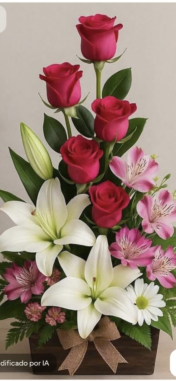 Tall arrangement of red roses, white lilies, and pink blooms in a wooden box with a burlap bow