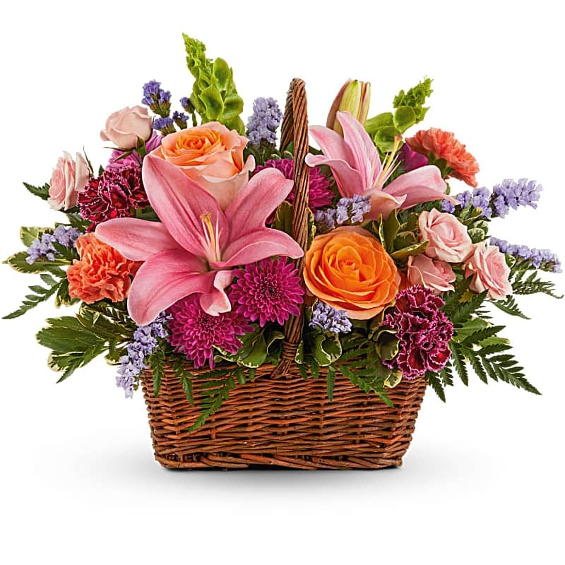 Blooming Joy Bouquet - Like an island sunrise, this basket of orange and pink blooms are a glowing reminder of life's greatest joys. This bouquet features orange roses, light pink spray roses, pink asiatic lilies, burgundy carnations, orange carnations, bells of Ireland, purple cushion spray chrysanthemums, blue sinuata statice, variegated pittosporum and leatherleaf fern. Delivered in a Rectangular Basket with Handle. Orientation: One-Sided