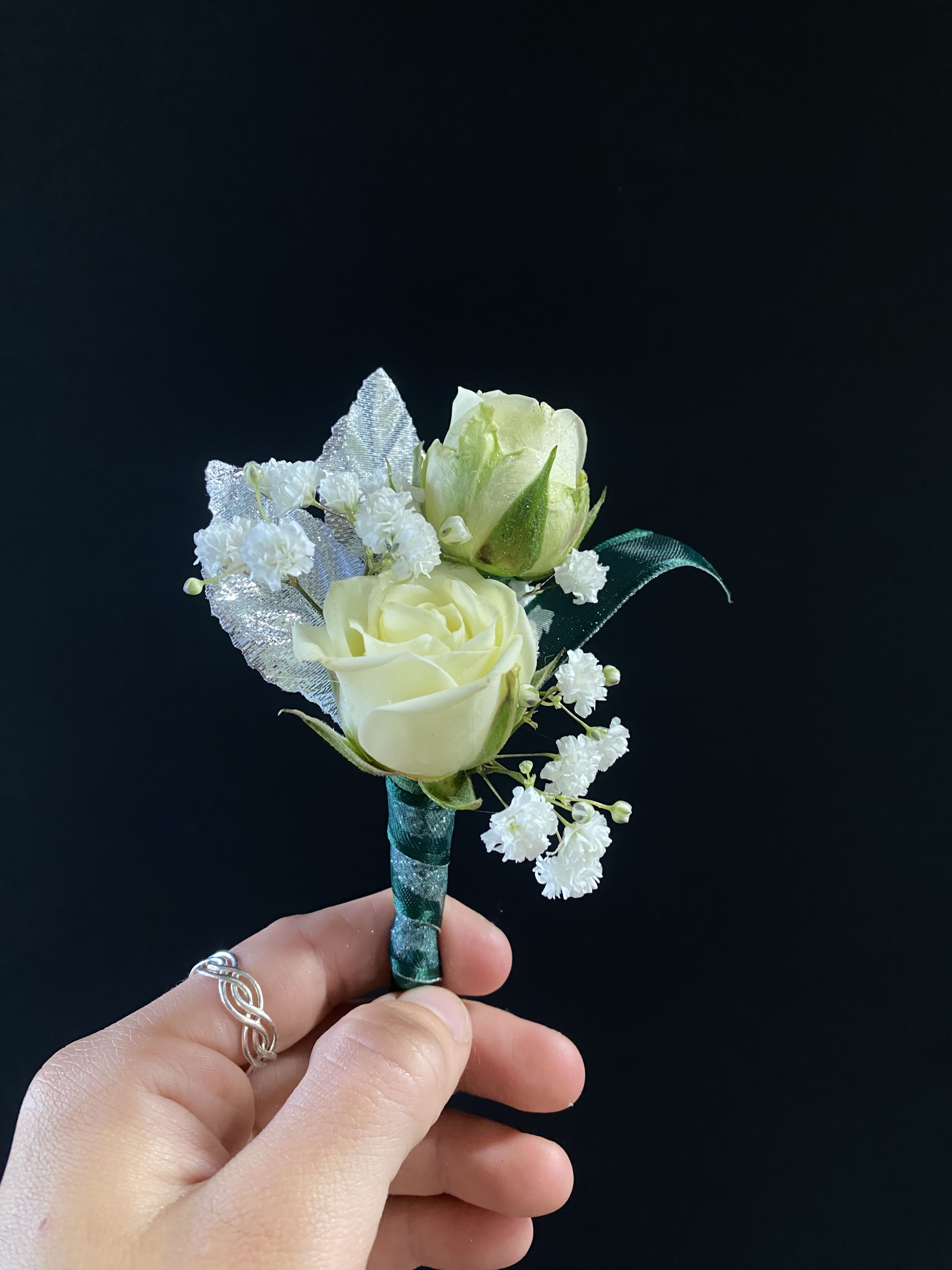 Cream rose boutonniere with white filler flowers and silver glitter leaves, wrapped with green ribbon