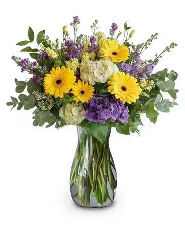 Radiant Garden - Brighten her day with this garden-inspired design featuring vibrant yellow gerberas, lavender blooms, and soft white hydrangeas nestled among lush greenery—an arrangement that speaks of love and admiration. 