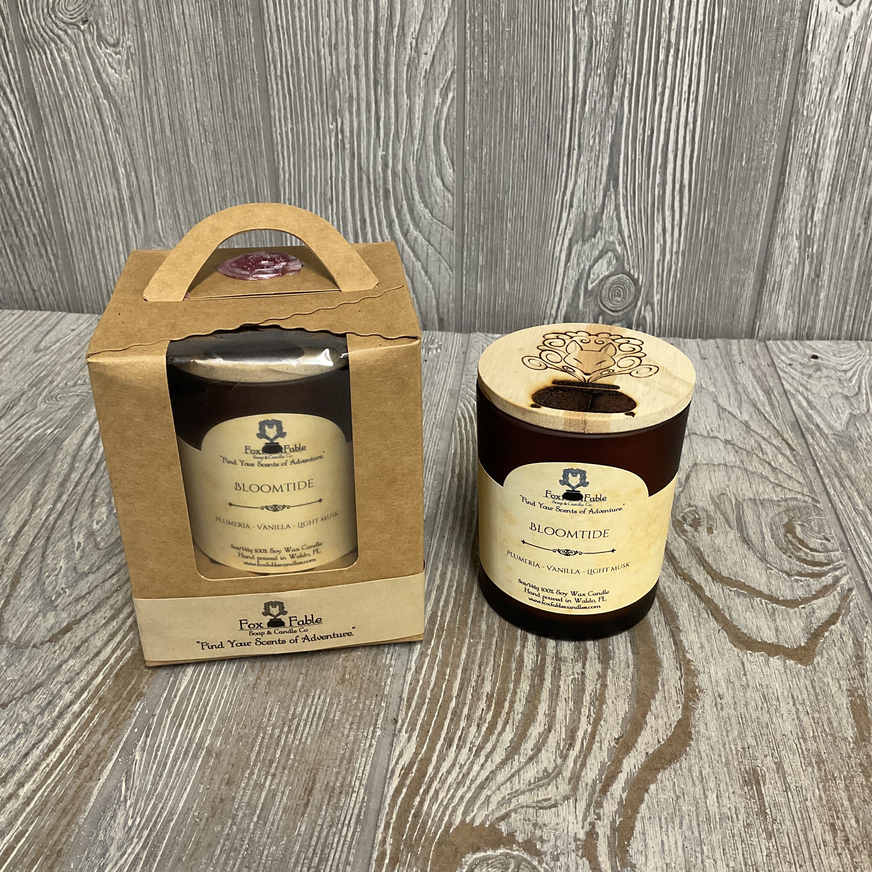 Brown glass scented candle with wooden lid and matching candle packaged in a kraft gift box