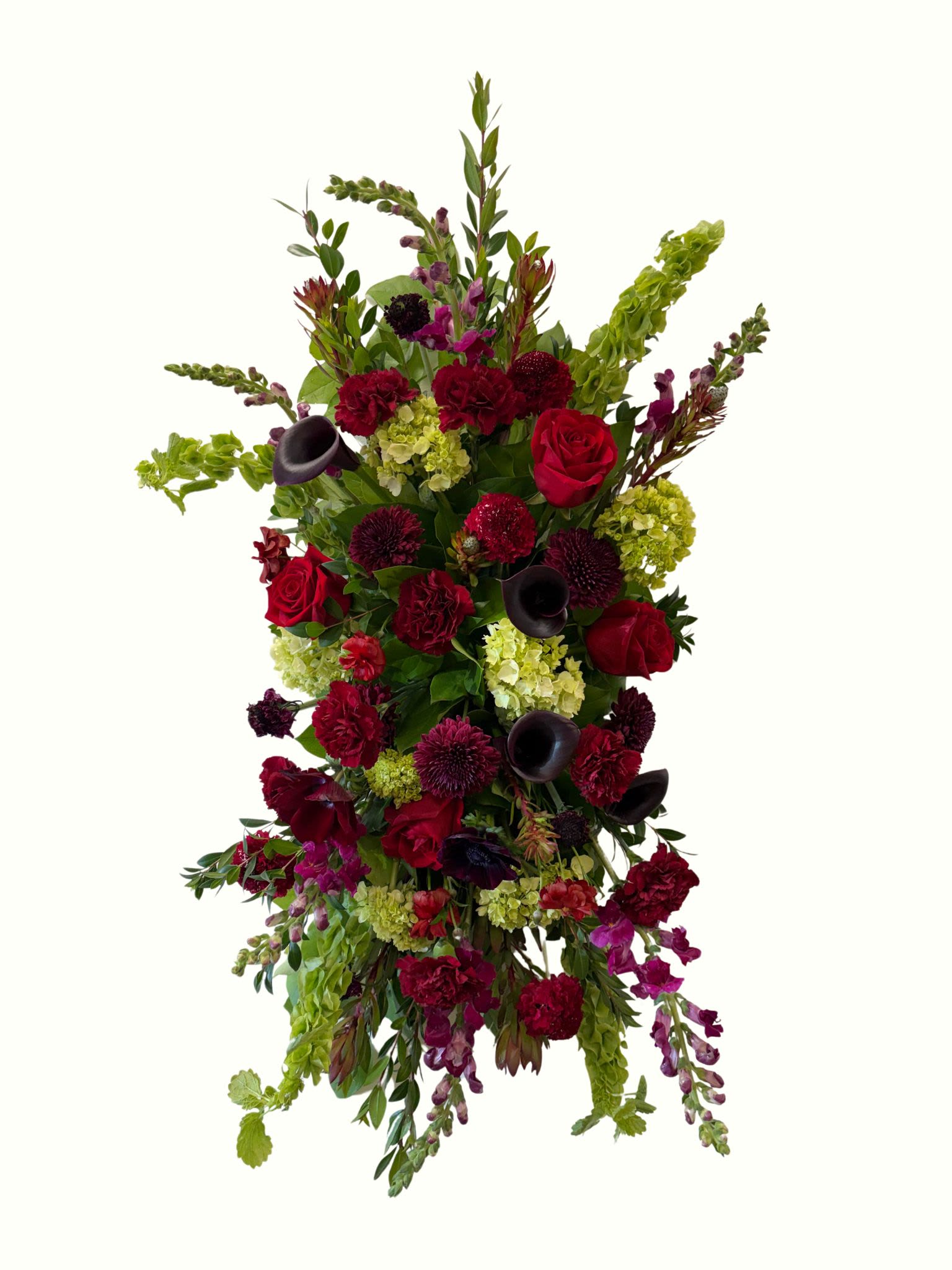 Deepest Devotion Standing Spray  - "Deepest Devotion" is a stunning and elegant funeral floral spray designed with a rich palette of deep reds and burgundy, bold hues of eggplant and wine, with natural colors and textures of greens. This striking arrangement evokes a sense of profound respect and heartfelt condolences, honoring the memory of the departed with dignified beauty.  This design can be translated to all formats for service, including caskets, baskets, cremation wreaths, and vased arrangements, just let our designers know to use the "Deepest Devotion" style palette. 
