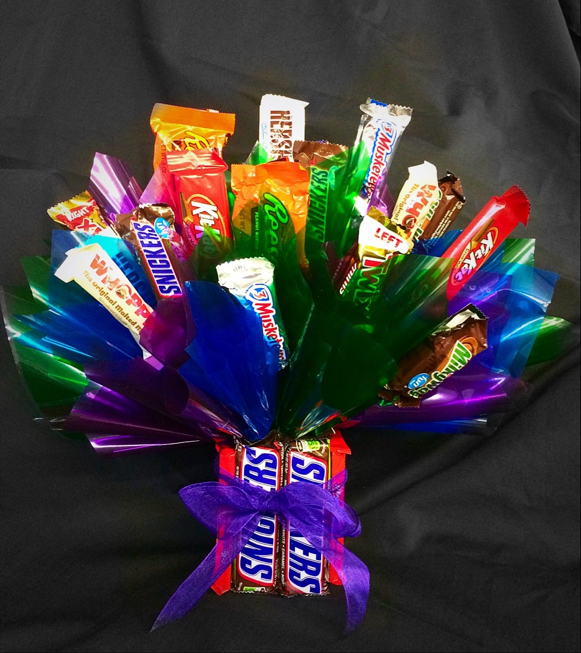 Candy bouquet of assorted chocolate bars with colorful cellophane and a purple bow base