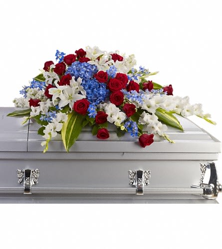 Red, white, and blue casket spray with roses, lilies, and hydrangeas on a silver casket.