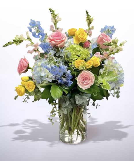 Garden Delight - Garden Bliss is a joyful celebration of color and natural beauty, inspired by a blooming spring garden. Soft pink roses, sunny yellow roses, and lush blue and green hydrangea are artfully arranged with delicate snapdragons and fresh greenery for a light, airy feel. Designed in a clear glass vase, this vibrant arrangement brings a sense of happiness, comfort, and effortless elegance to any space. Perfect for birthdays, celebrations, or simply to brighten someone’s day, Garden Bliss delivers beauty in full bloom.