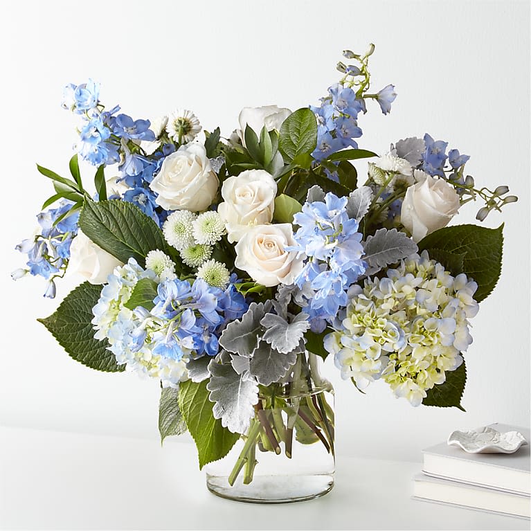 Blue and white flowers arranged in a clear glass vase