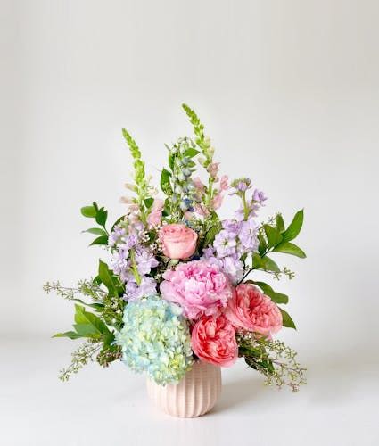 Fair and Beauty - This design combines delicate shades of blush pink and rich purples, featuring garden roses, hydrangeas, peonies, and gorgeous delphiniums. Accents stock and lush greenery add texture and depth, creating a lush and luxurious bouquet that is as lively and sophisticated as its namesake.