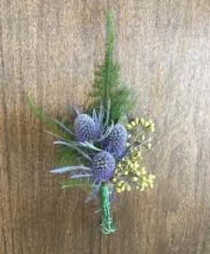Small boutonniere of purple thistle-like blooms with yellow accents and greenery tied with green tape