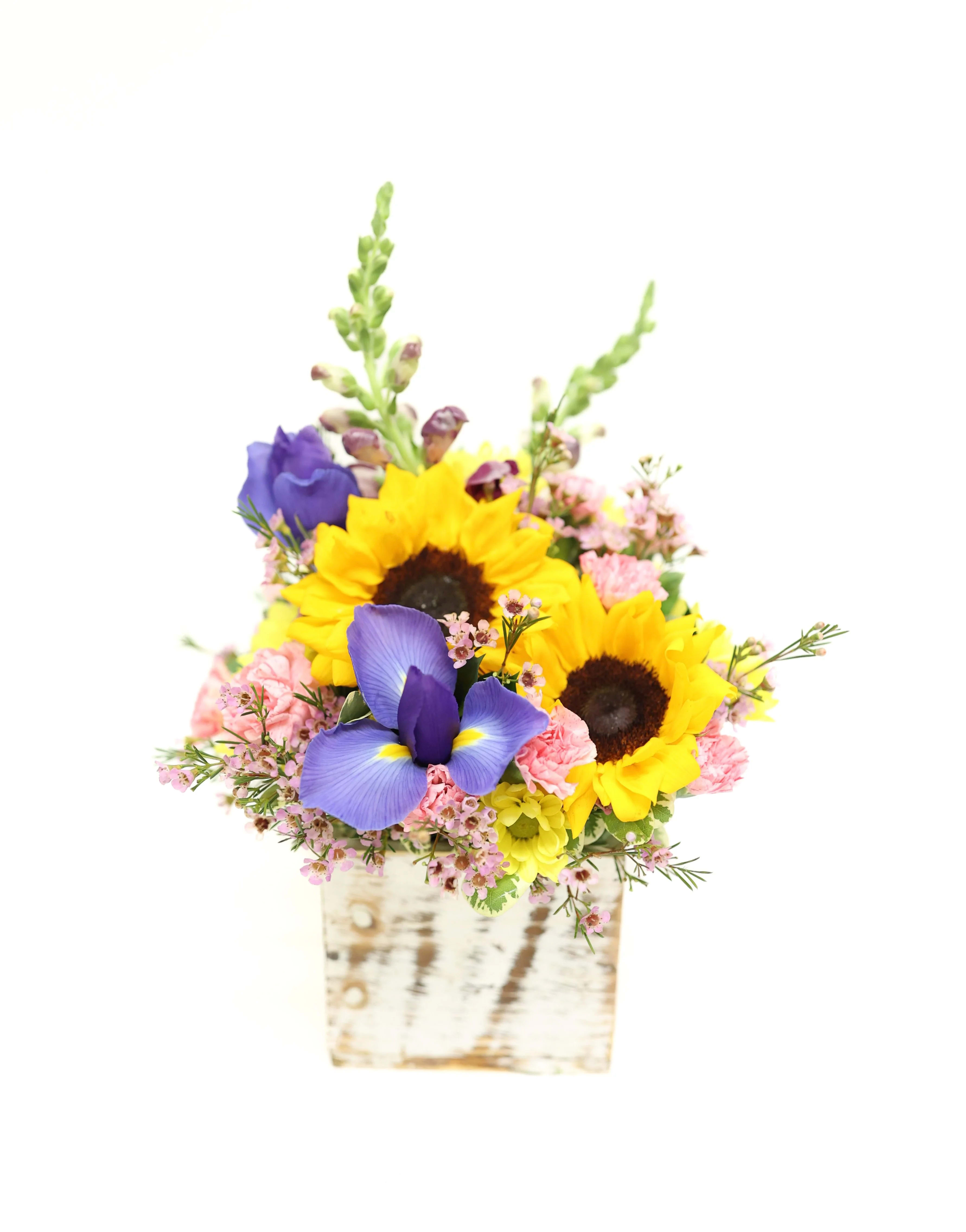 Sunflowers and purple irises in a rustic wooden container