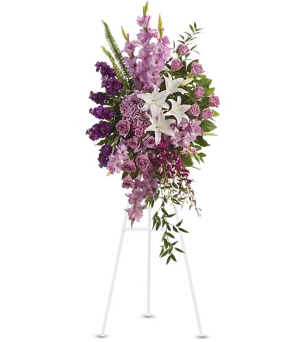Tall lavender and purple standing spray with white lilies on a white easel