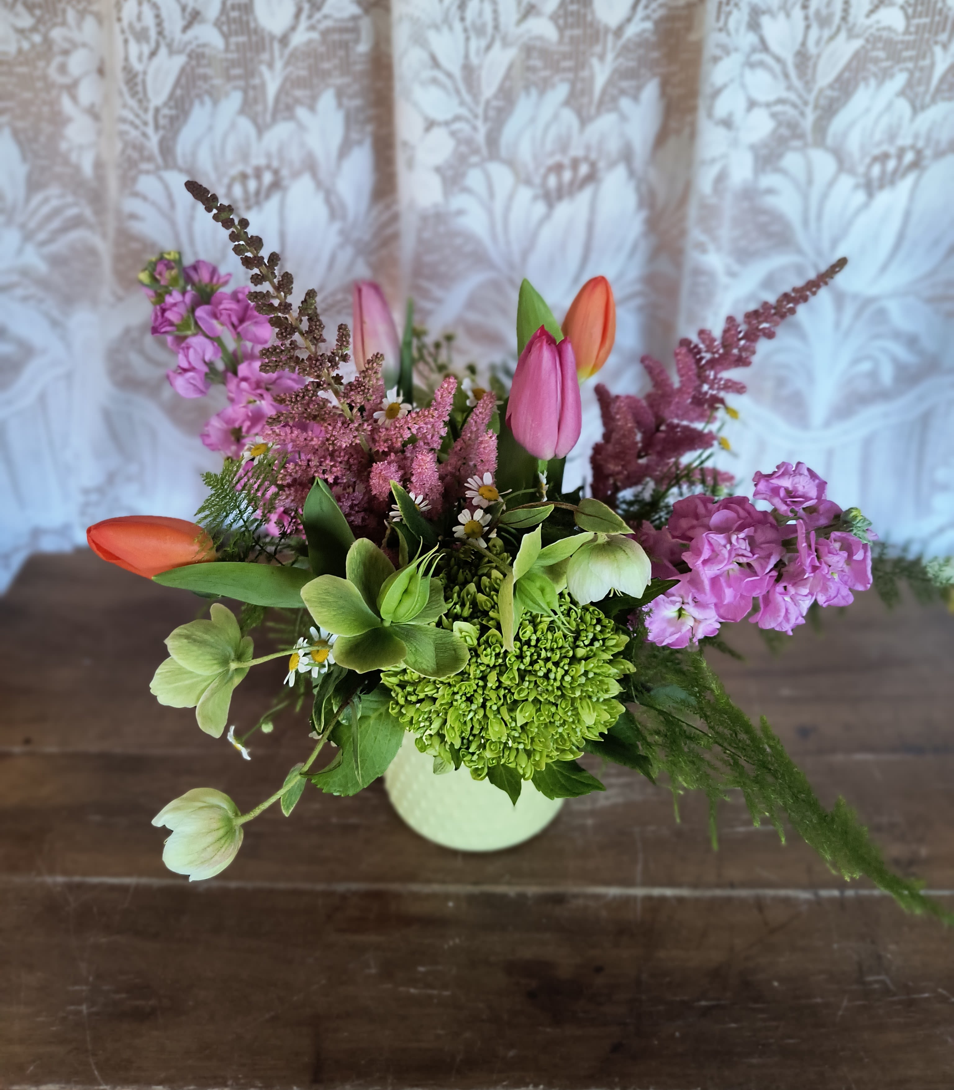 Invigorating - Spring at a new level of elegance with a low and lush arrangement. A beautiful spring mix of spring garden flowers such as but not limited to, tulips, hydrangea, helleborus, astilbe, stock, feverfew and plumosa. Colors may vary depending upon availability.
