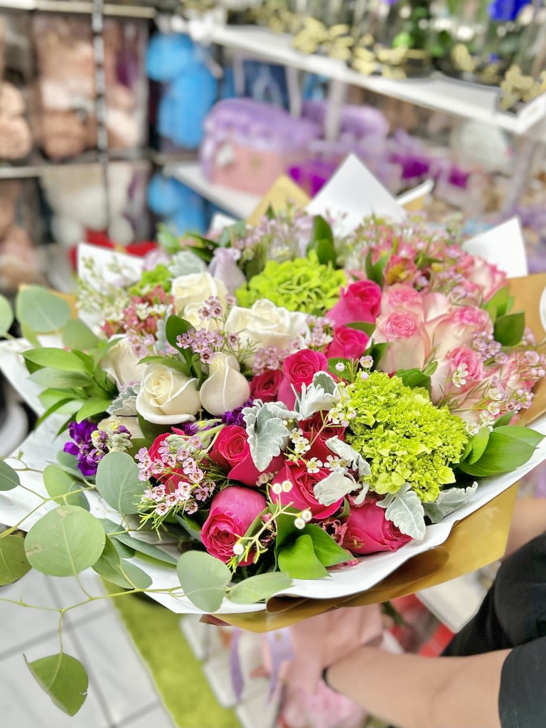 Mixed bouquet of hot pink and ivory roses with lime green blooms in white and gold wrapping