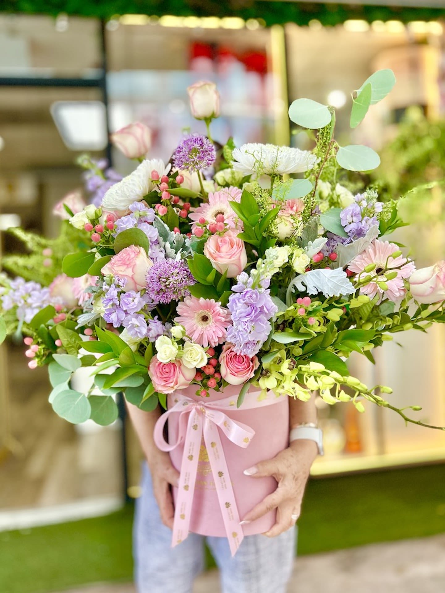 Large pastel flower arrangement with pink roses, gerberas, and lavender blooms in a pink hatbox with ribbon.
