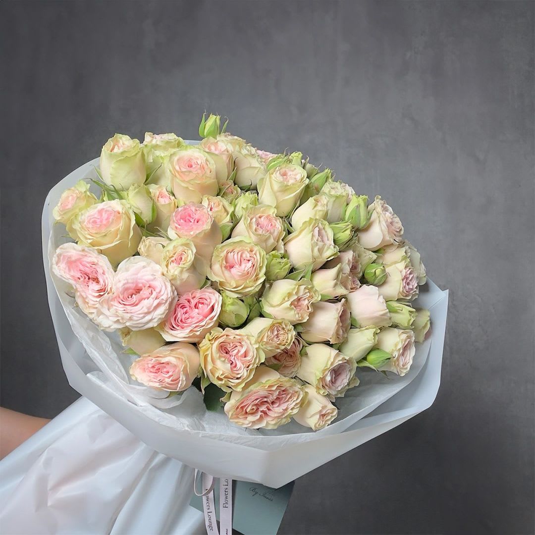 Large bouquet of pale cream and blush pink roses wrapped in white paper