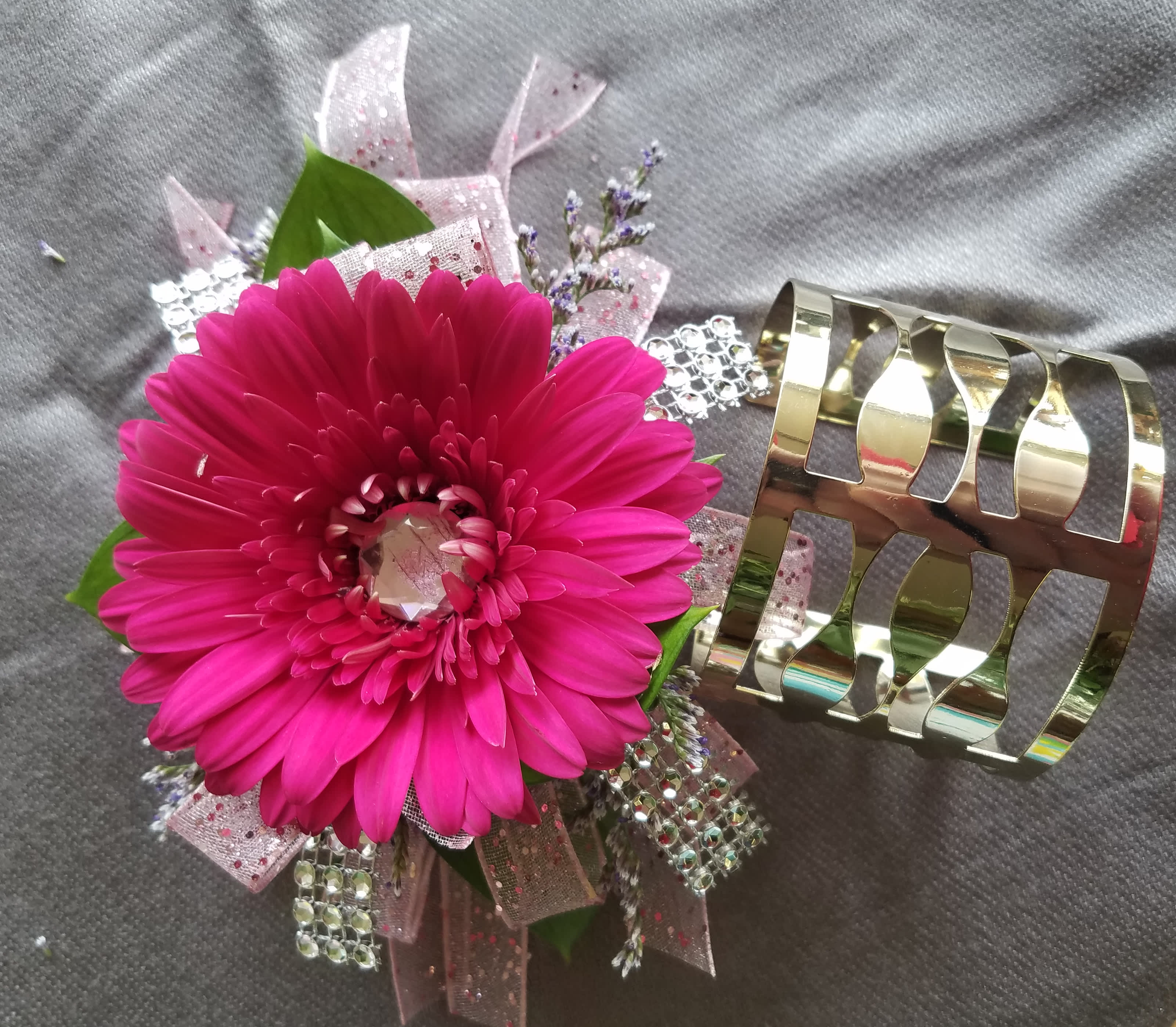 Corsage Gerber Daisy Premium - This corsage has a Gerber Daisy with rhinestone of common colors with greens, filler, upgraded bling, and upgraded bracelet. We have all sorts of ribbon from lime green sparkle to animal print, just tell us in the special instructions what your looking for! You may also send us a picture of the dress or inspirations to our email address lvfloral@gmail.com just make sure to include your name and order number.    ALL corsage/boutonniere orders will be ready for PICK UP ONLY between 1pm-4pm the day of the event. 
