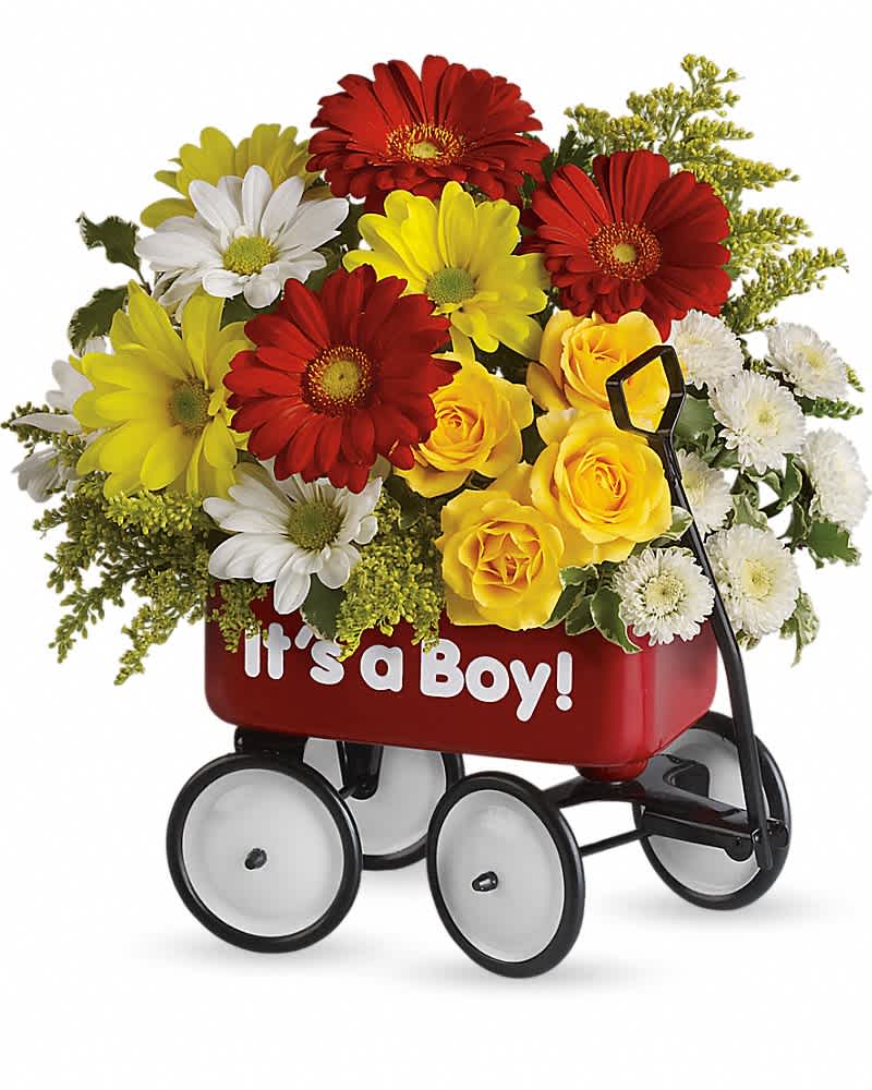 Bright mixed arrangement of red gerberas, yellow roses, and white daisies in a red 'It’s a Boy!' toy wagon