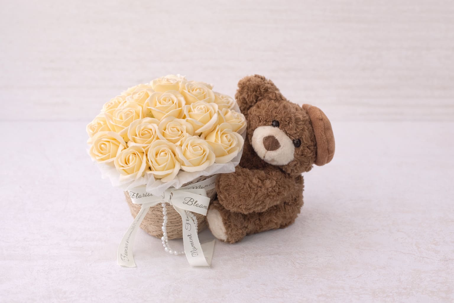 [SOAP FLOWER]Cream roses and teddy bear arrangement - A charming and timeless gift, this arrangement features a delicate dome of soft ivory soap roses, beautifully arranged in a rustic woven basket. Each rose is carefully crafted to resemble real blooms, offering long-lasting elegance without the need for maintenance.  Paired with an adorable plush teddy bear, this design brings a warm, heartfelt touch—perfect for expressing love, appreciation, or comfort. Finished with elegant ribbon details and subtle pearl accents, it creates a soft, romantic aesthetic that feels both cozy and refined.  Ideal for birthdays, anniversaries, or simply sending a sweet surprise, this piece is a keepsake that lasts far beyond fresh flowers.