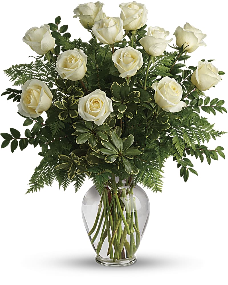 Tall arrangement of white roses with lush foliage in a clear glass vase
