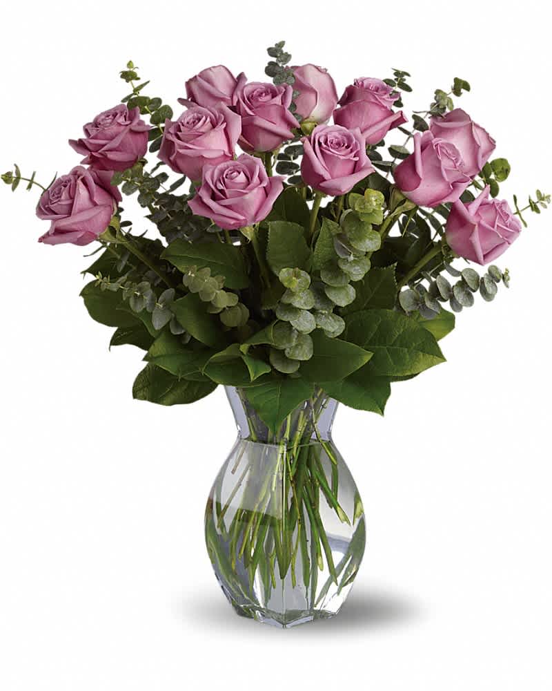 Arrangement of lavender roses with eucalyptus in a clear glass vase