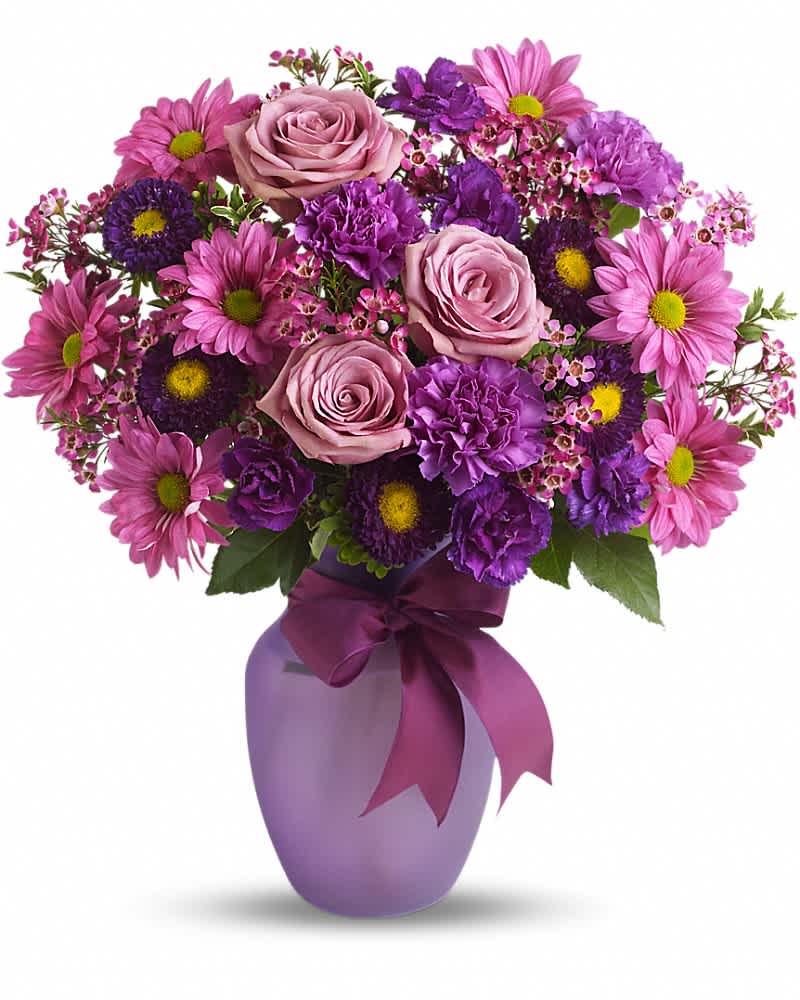 Purple and pink bouquet with roses, carnations, and daisies in a frosted lavender vase with a satin bow