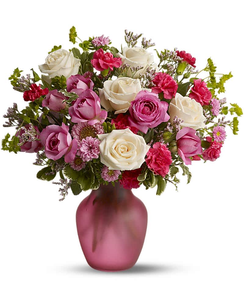 Pink and white roses with pink carnations and mums arranged in a pink frosted glass vase