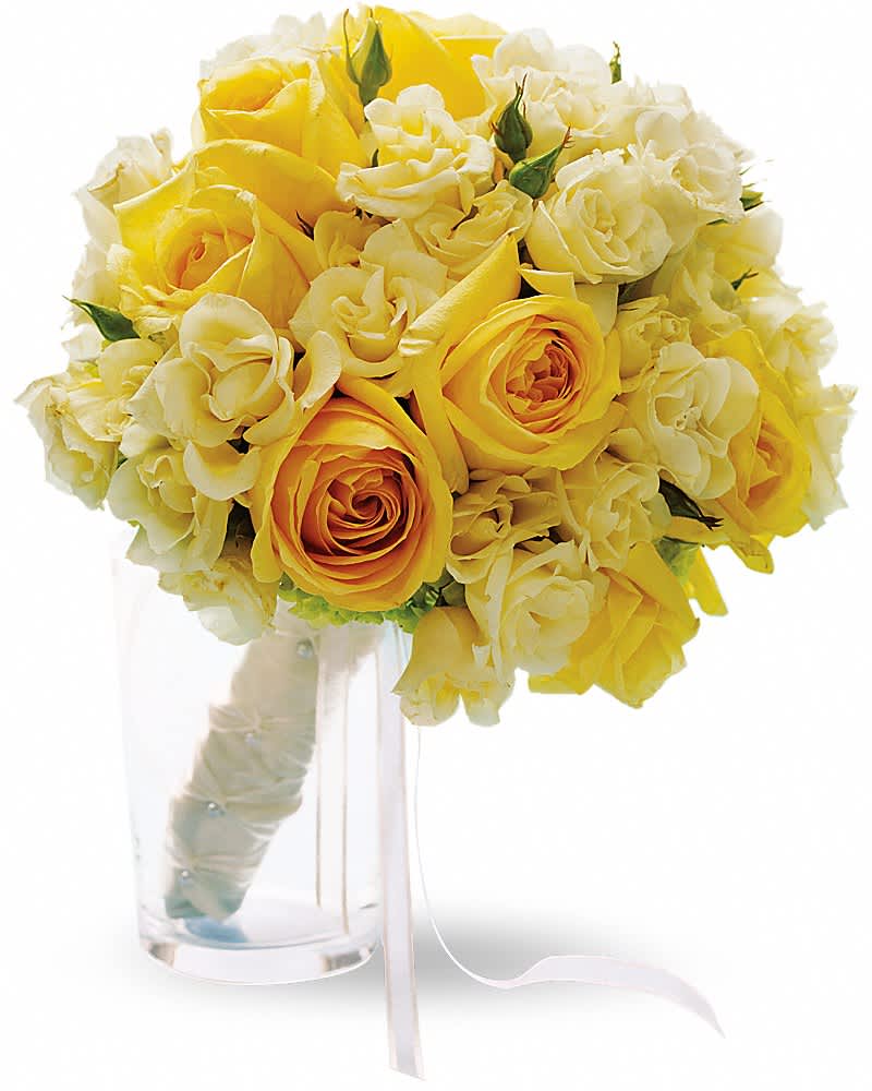 Hand-tied bouquet of yellow and ivory roses with wrapped handle in a clear glass vase