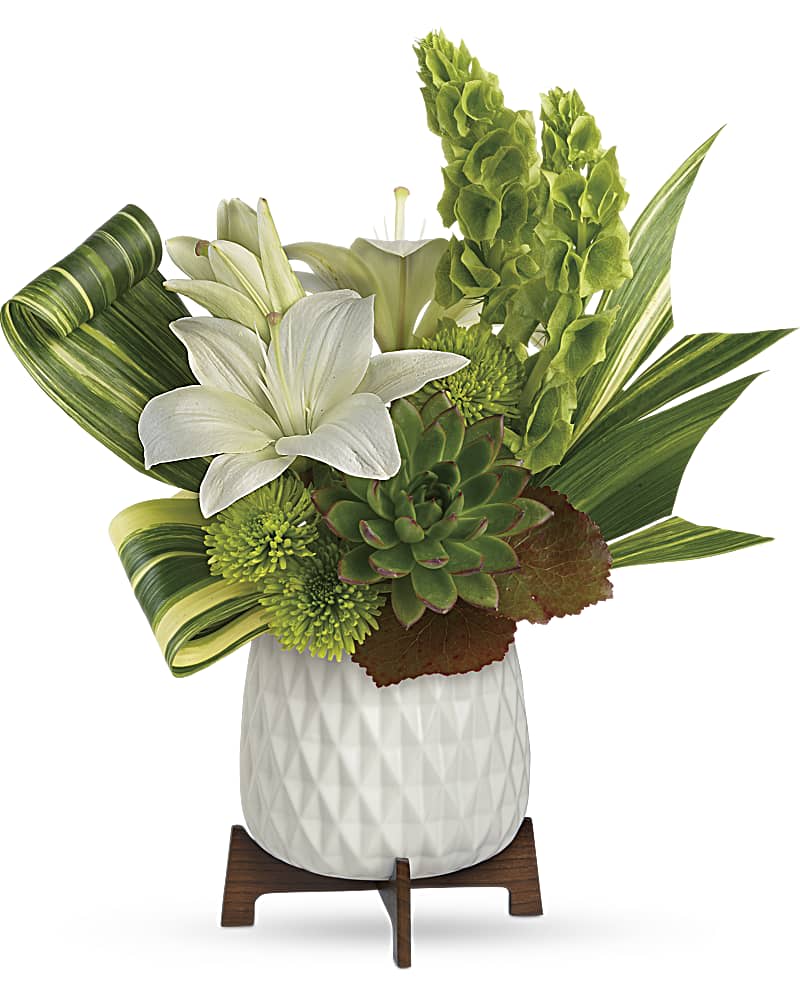 Modern arrangement with white lilies, green bells of Ireland, succulents in a white pot on a wooden stand.